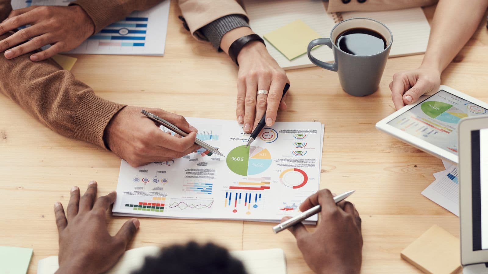 Equipe analisando relatórios e gráficos sobre a mesa de trabalho