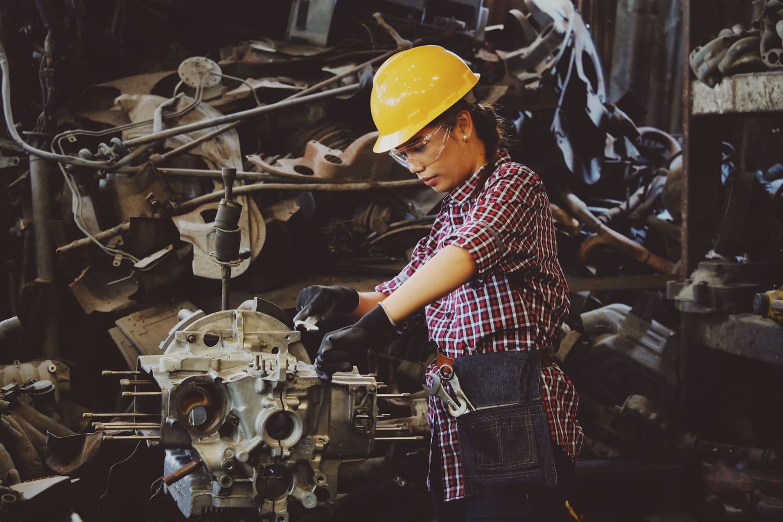 Trabalhadora com capacete e óculos de proteção operando em ambiente industrial
